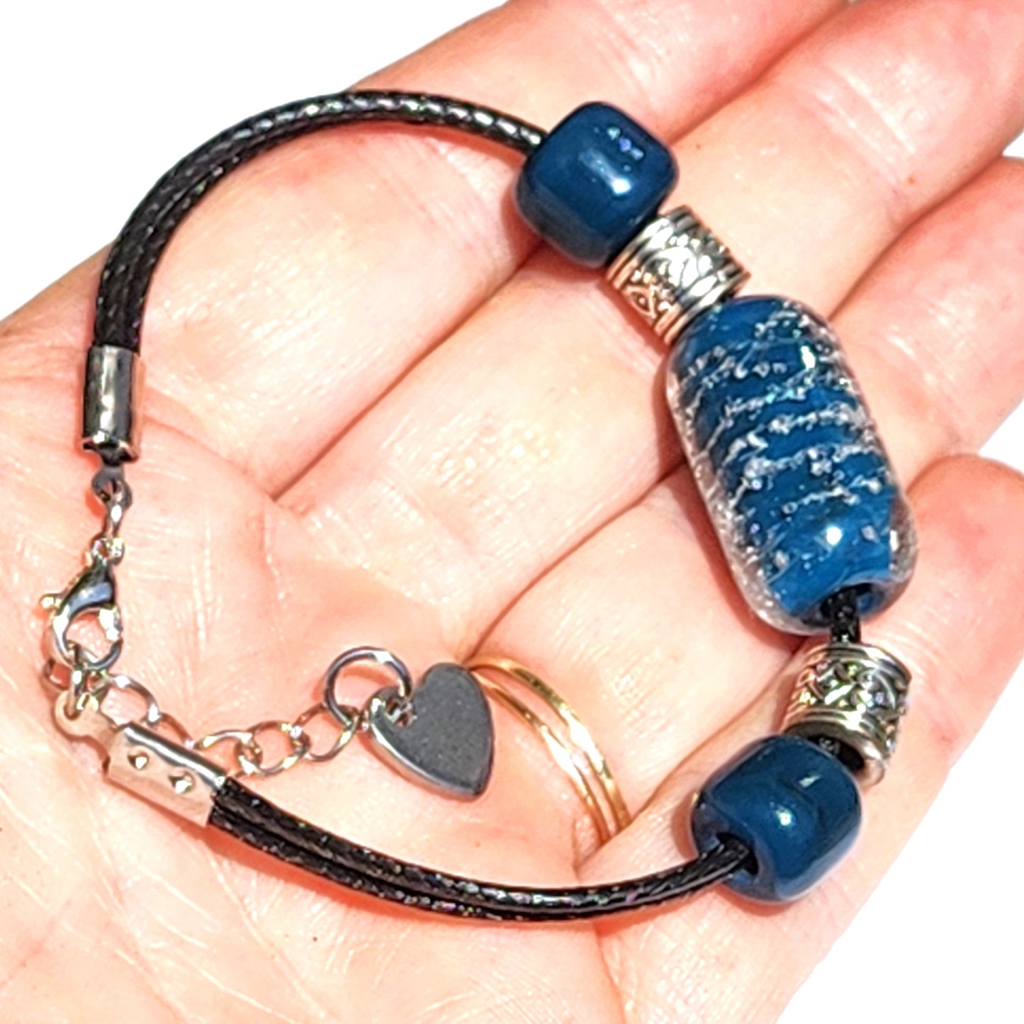 Handheld Ocean Blue cremation bracelet with heart charm and glass urn bead, part of memorial jewelry set for ashes.