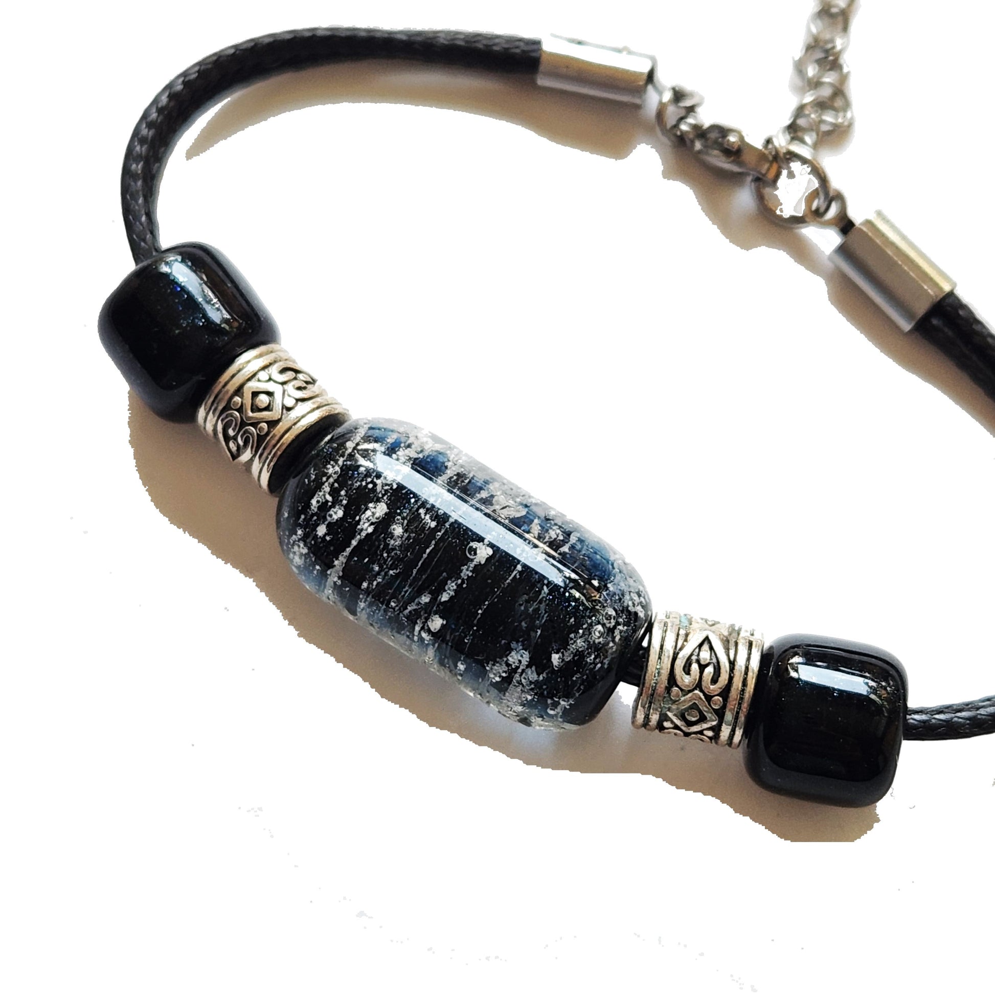 Bracelet with ashes featuring a central cremation bead in black and silver, flanked by heart-accented metal spacers on a black leather cord. Handmade Remember Me urn bracelet for memorial ceremonies and daily wear.