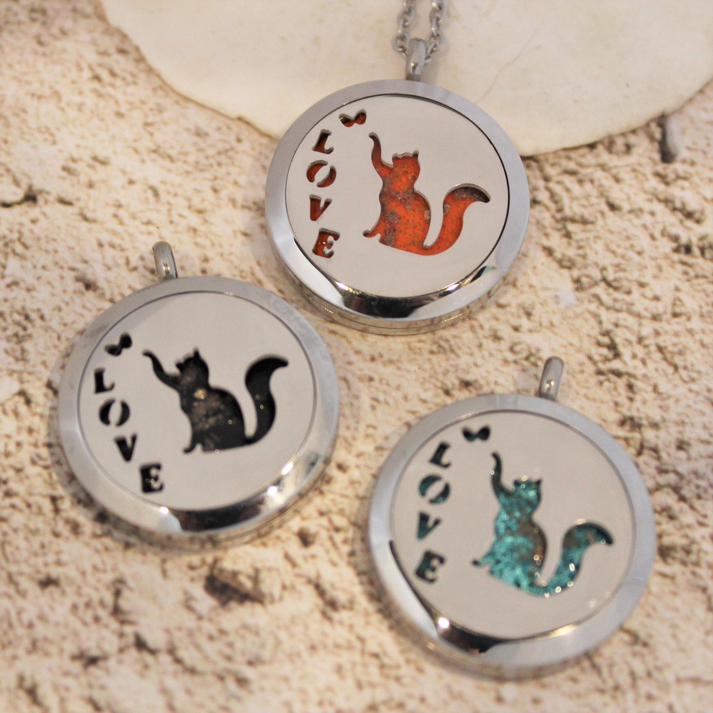 Three circular pendants with cat illustrations and 'LOVE' text on a textured surface.