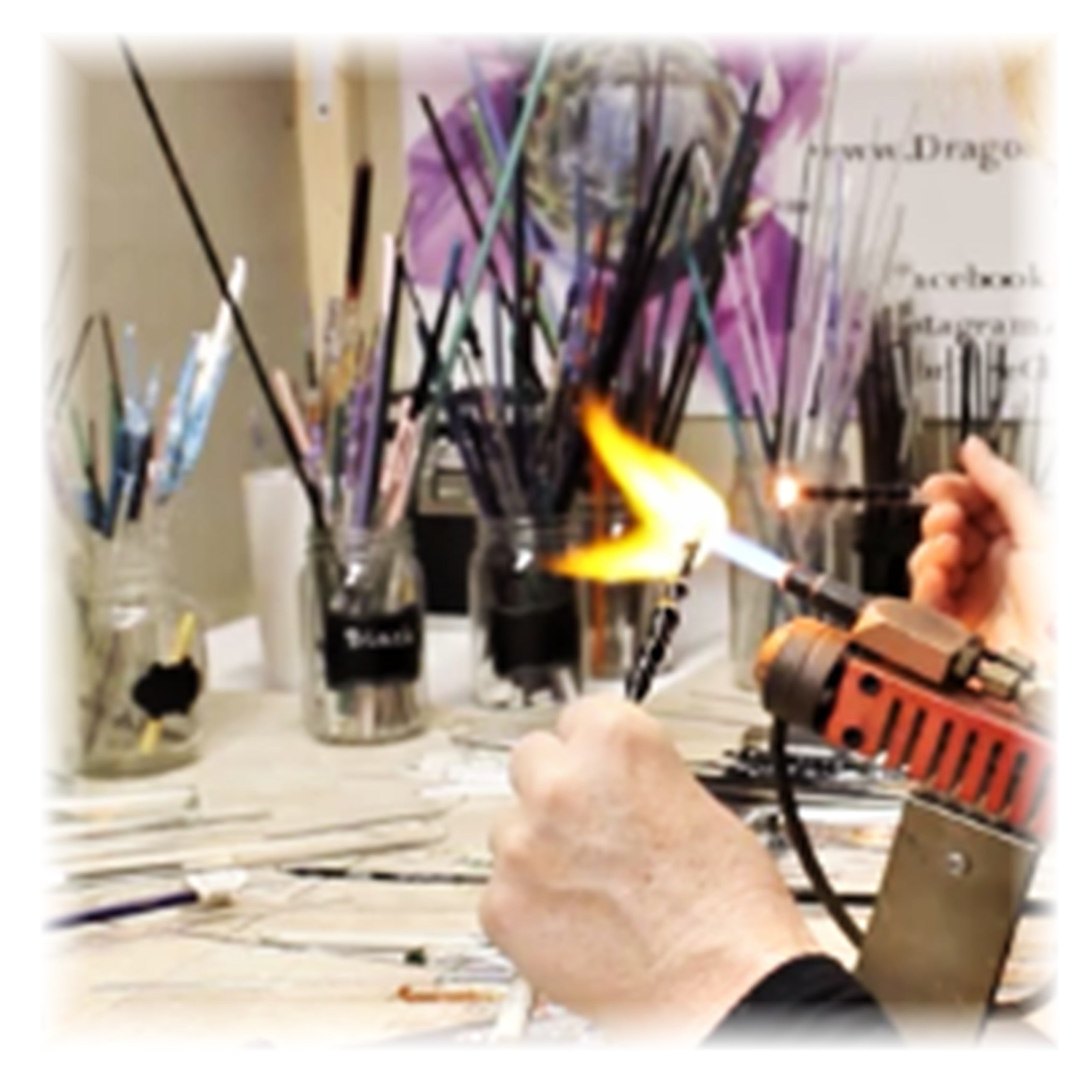 Showing a lampworking torch with the fire on and a glass rods in the flame. Getting ready to blow glass