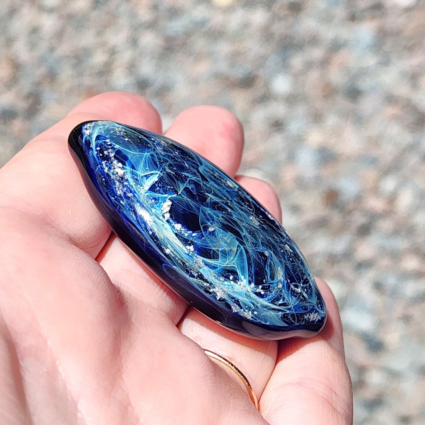 Galaxy Cremation Touchstone with ashes in swirling blue, turquoise, and white glass. Memorial glass keepsake for remembrance ceremonies.