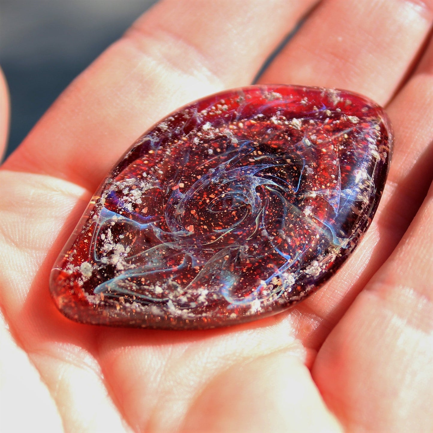 Galaxy Cremation Touchstone in red with swirling galaxy design, infused with ashes. A handmade memorial glass keepsake for remembrance ceremonies.