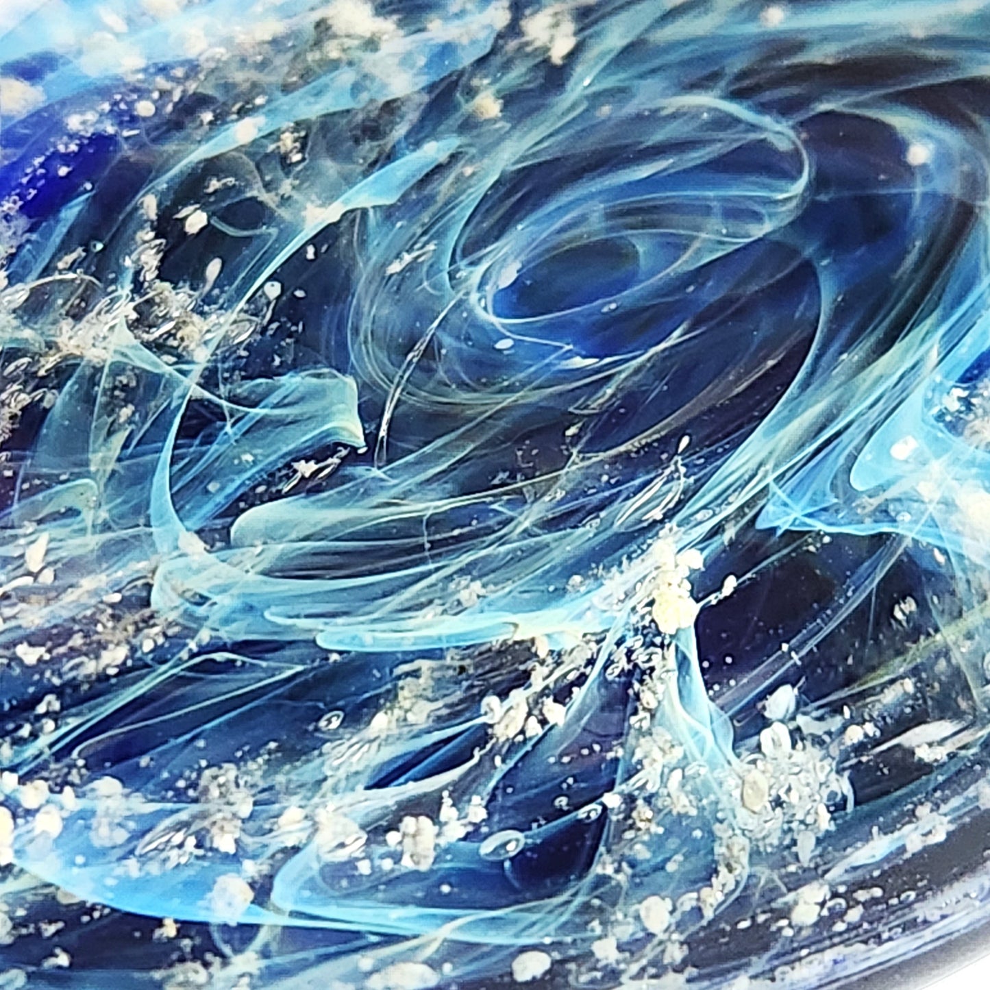 Galaxy Cremation Touchstone with swirling blue, turquoise, and white glass design infused with ashes. A unique memorial glass keepsake for remembrance.