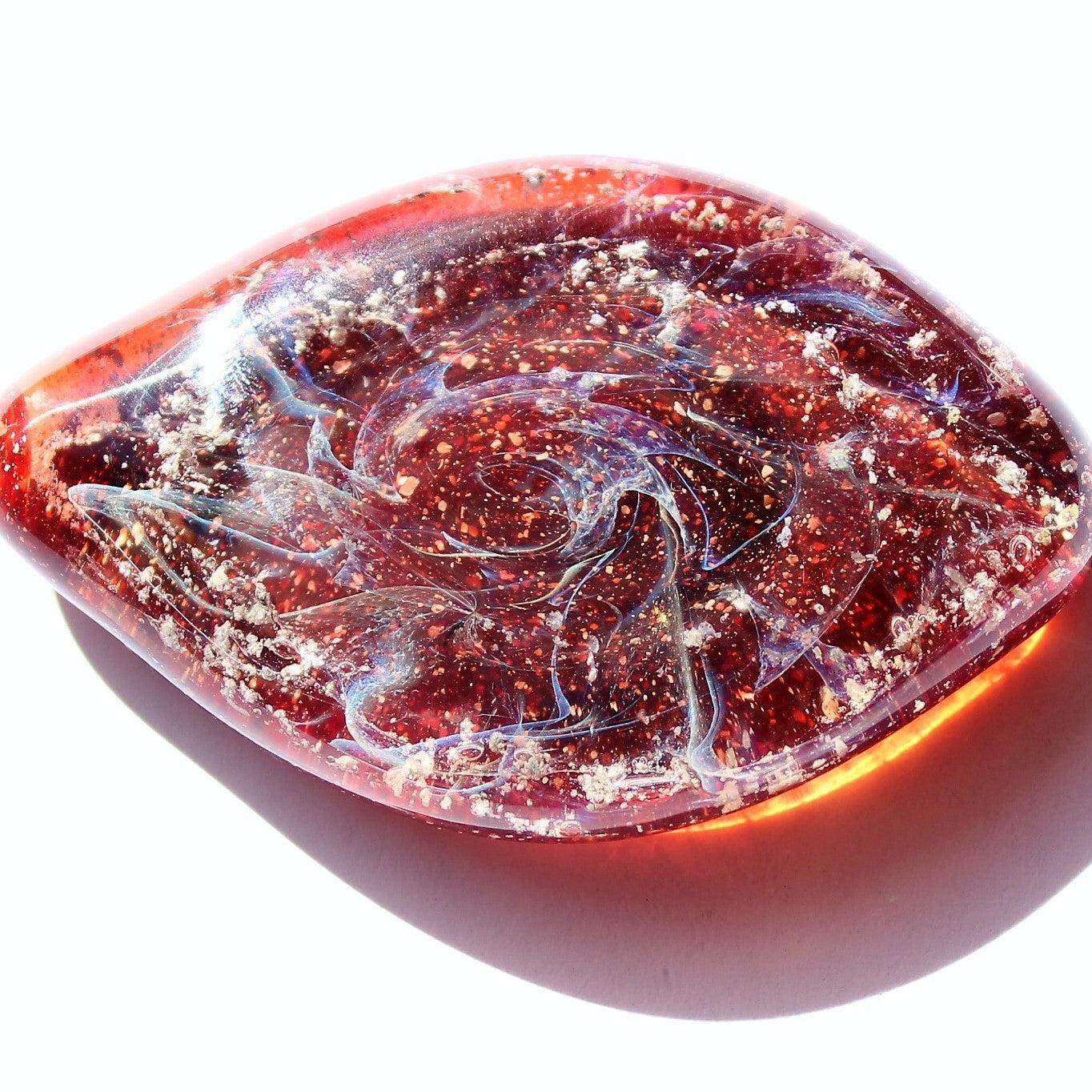 Galaxy Cremation Touchstone in red with swirling glass design and ashes infused, a handmade memorial glass keepsake for honoring loved ones.