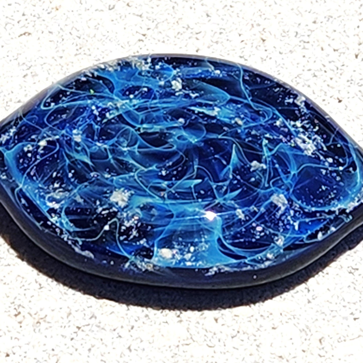 Galaxy Cremation Touchstone with swirling blue, turquoise, and white patterns, a memorial glass keepsake infused with ashes for remembrance.