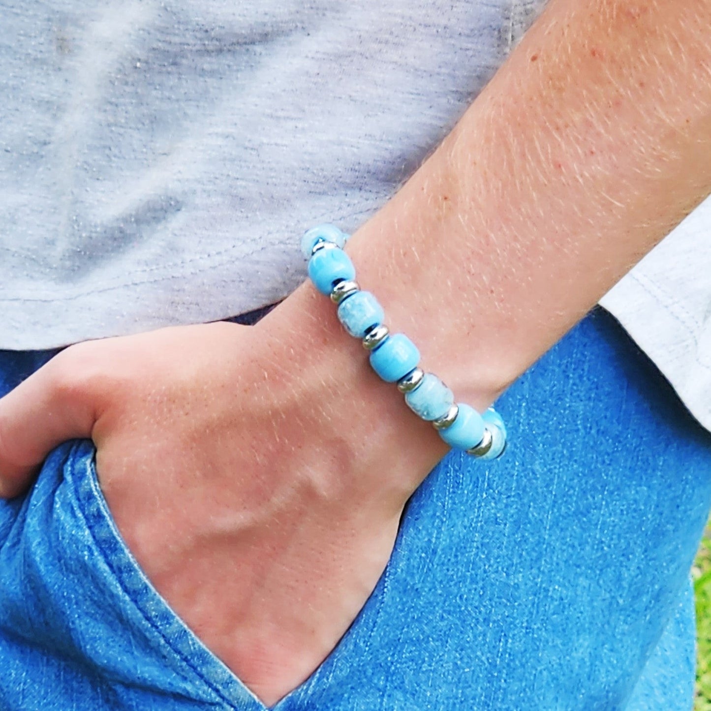 Ocean Blue Memorial Bracelet featuring ash-infused glass cremation beads and stainless steel spacers, worn on wrist for memorial tribute.