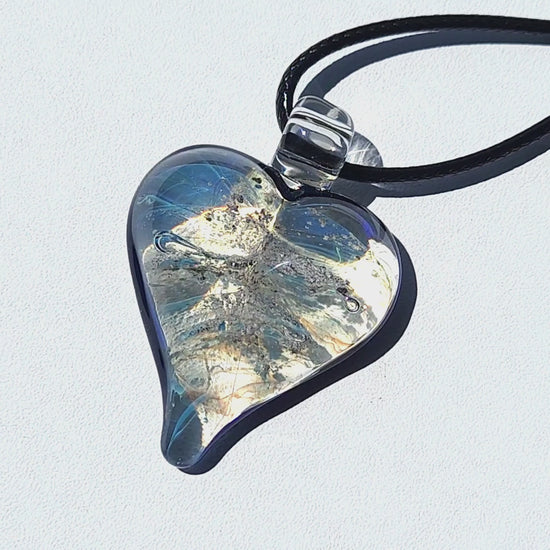 Heart cremation pendant with ashes in blue and silver shimmer, handmade glass memorial jewelry from the Forever in My Heart collection.