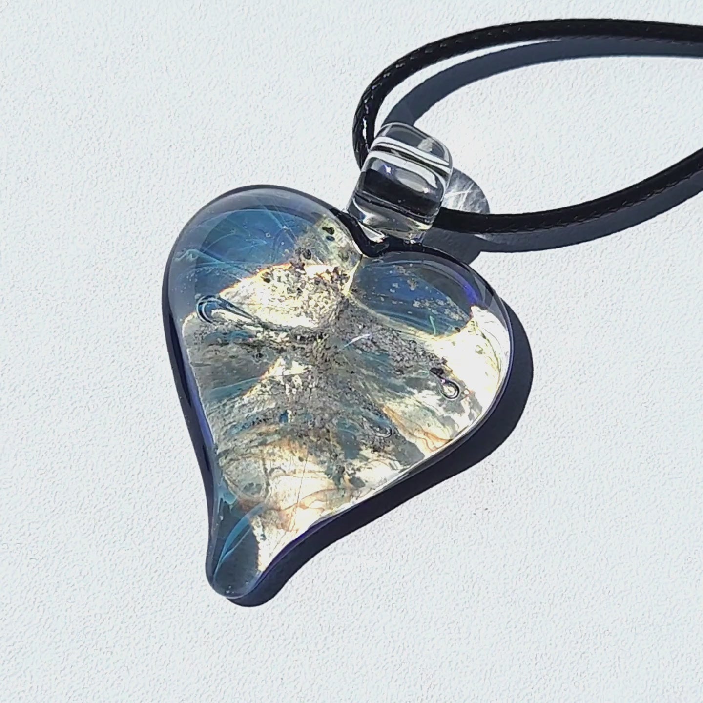 Heart cremation pendant with ashes in blue and silver shimmer, handmade glass memorial jewelry from the Forever in My Heart collection.